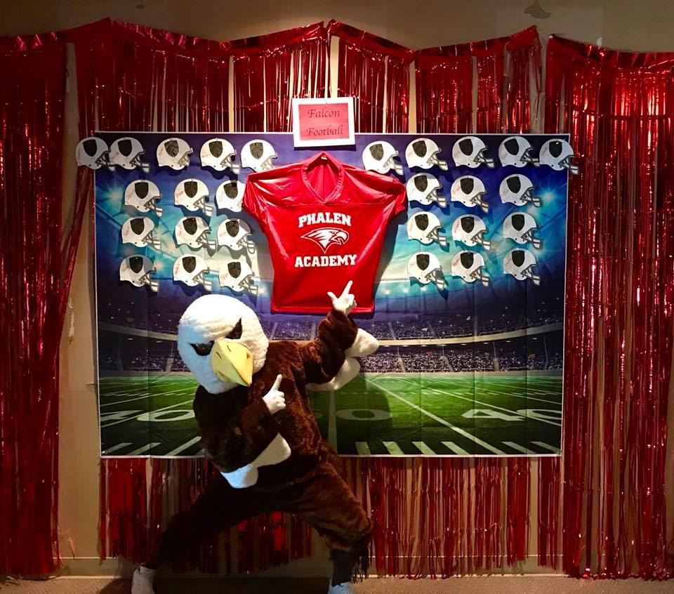 Phalen Falcon Mascot standing in front of bulletin football board. Phalen Falcon Mascot standing in front of bulletin football board.